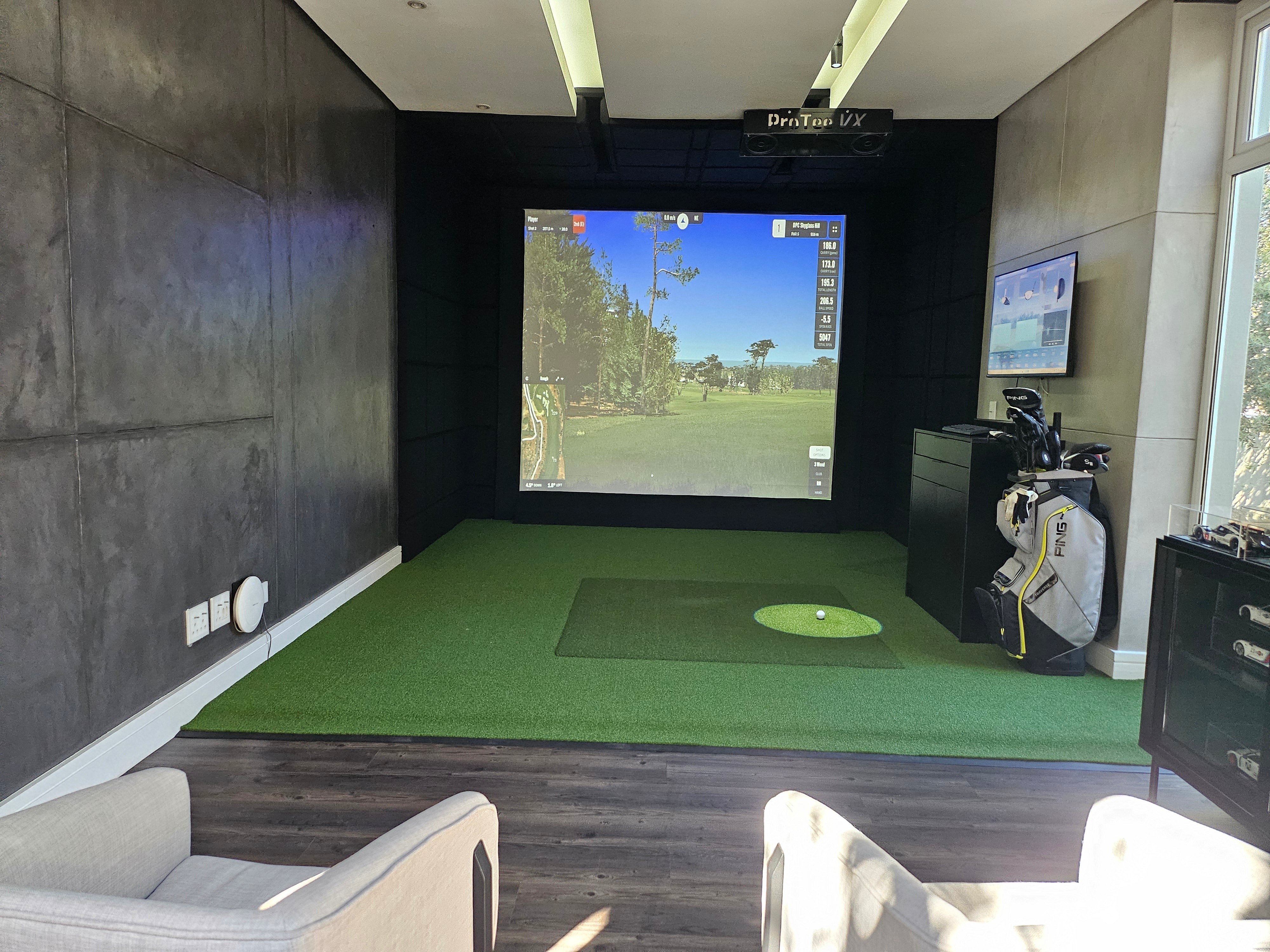 Bespoke residential indoor golf bay with ProTee VX overhead launch monitor, custom acoustic ceiling, and modern seating area.