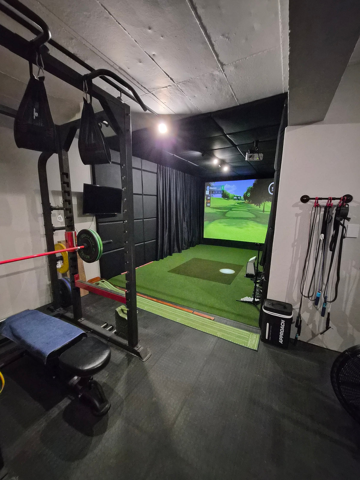 Multi-purpose garage setup combining a home gym squat rack with a custom golf simulator hitting bay in South Africa.