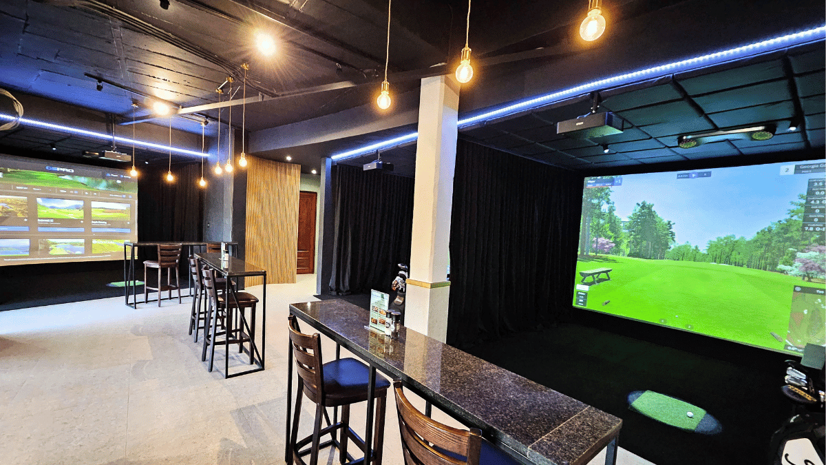 Custom multi-bay indoor golf simulator facility installation with high-impact screens, launch monitors, and bar seating in South Africa.