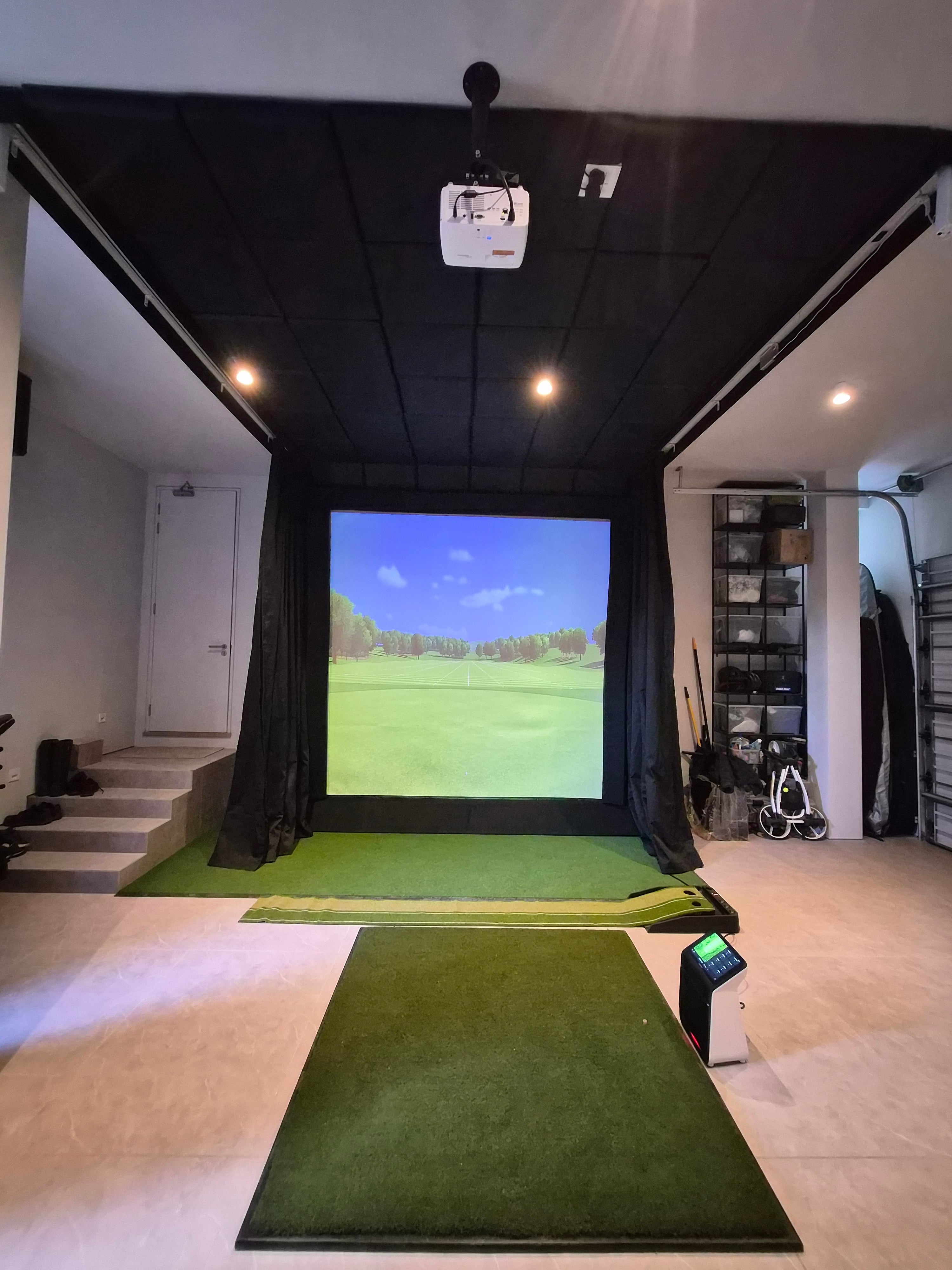 Full garage golf simulator room with padded ceiling, putting mat, overhead tracking unit, and floor launch monitor.